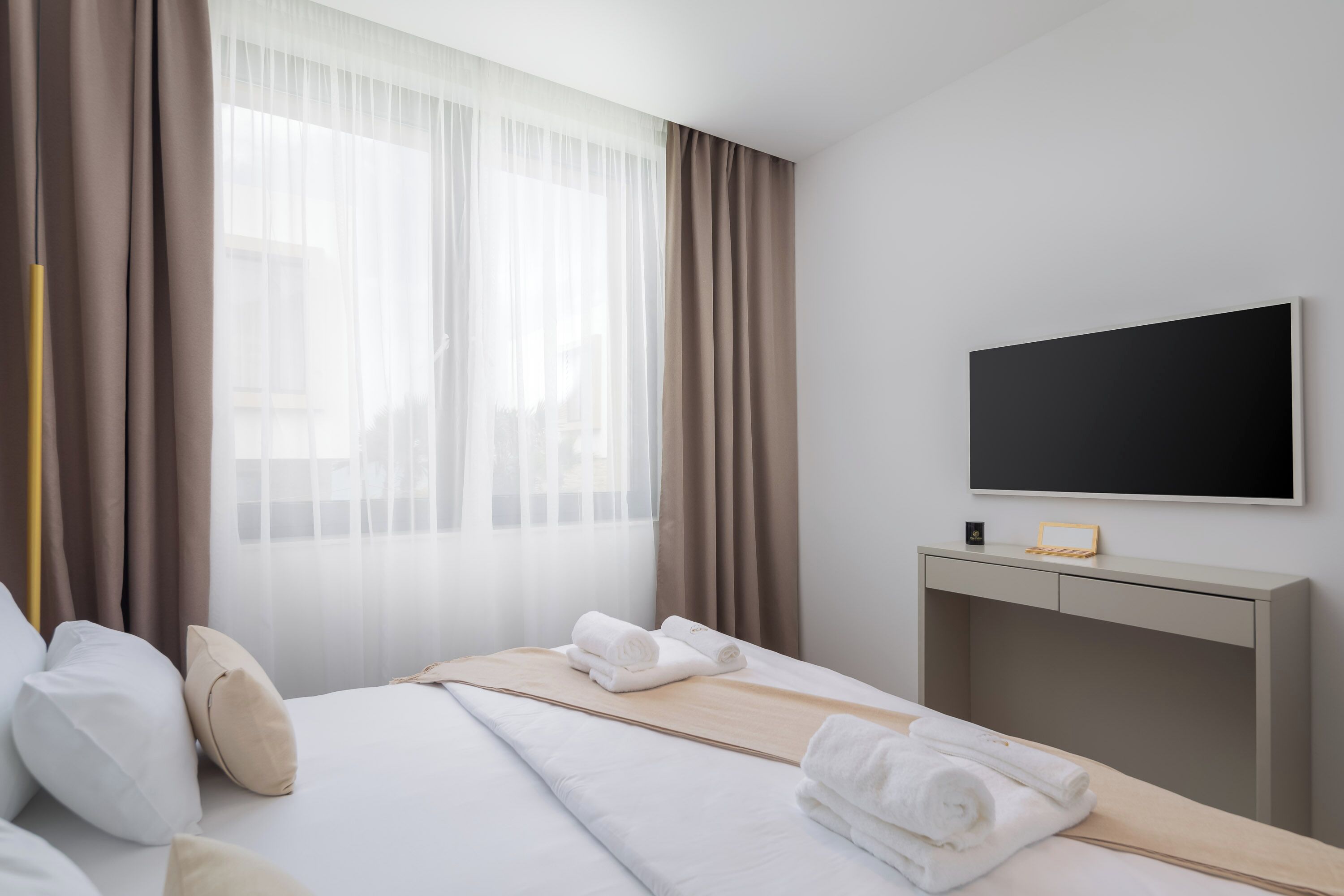 A hotel room with a bed, a TV, and a desk.