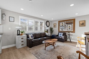 A modern living room with a sectional sofa, a coffee table, and a dining area with a small table and chairs.