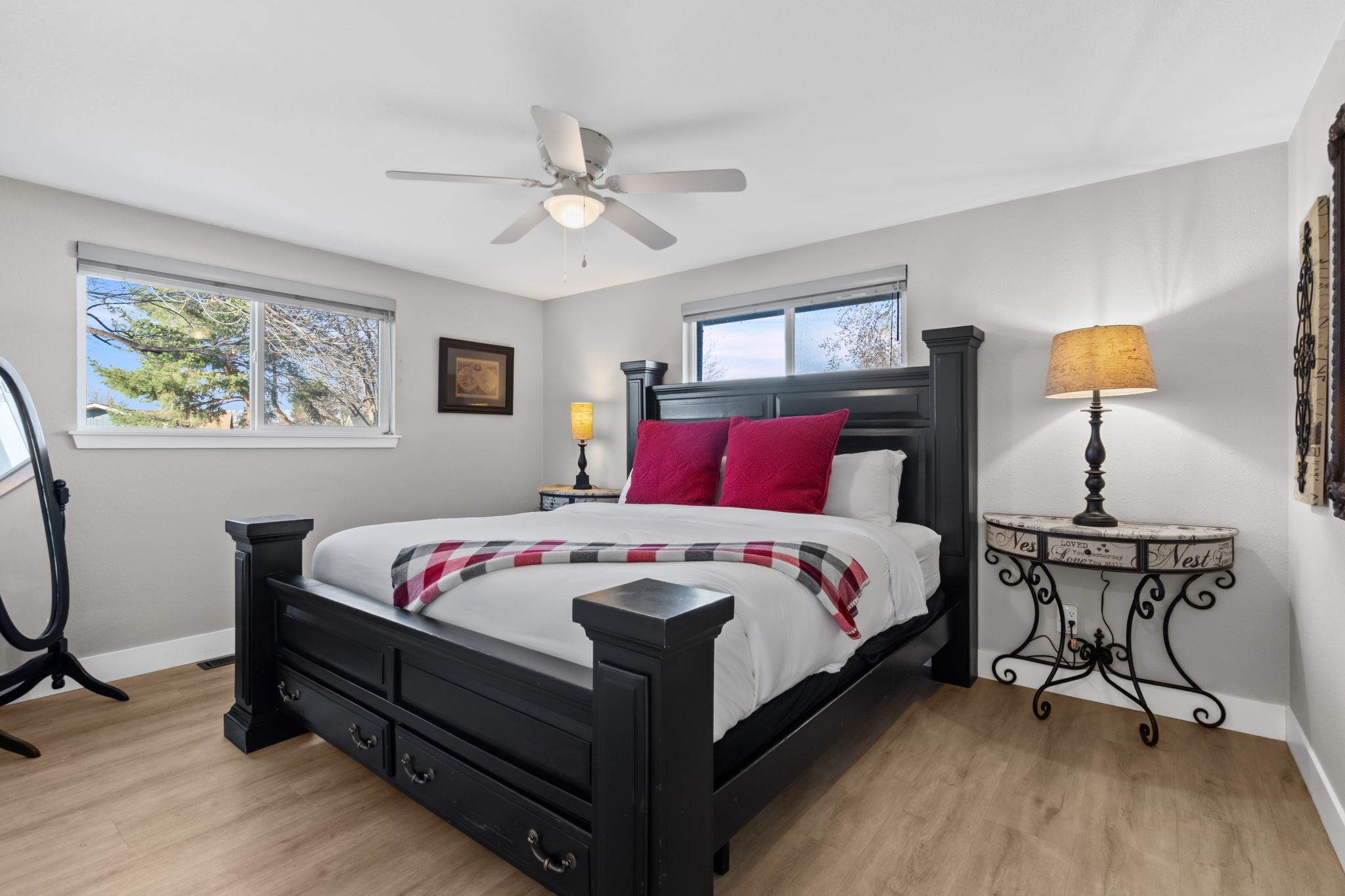 A bedroom with a bed, a ceiling fan, a nightstand, a lamp, and a window.