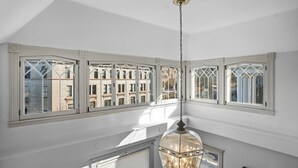 Una habitación con ventanas amplias, una lámpara colgante y vistas de edificios.
