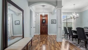 A hallway with wooden flooring, a bench, a dining area with chairs, and a chandelier. - Spacious 4-bedroom house with AC in fabulous Gulfport (Gulfport)