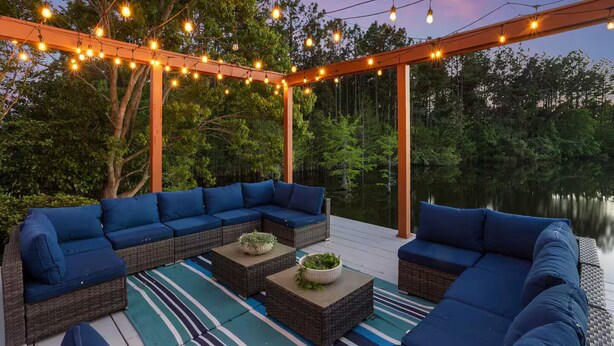 An outdoor deck with a blue sectional sofa, a coffee table, and a string of lights. - Spacious 4-bedroom house with AC in fabulous Gulfport (Gulfport)