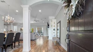 A spacious kitchen with a dark wood countertop, a dining area with a chandelier, and a hallway with a decorative plant. - Spacious 4-bedroom house with AC in fabulous Gulfport (Gulfport)