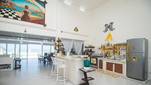A spacious kitchen with a large island, bar stools, and a refrigerator. - Casa do Sol by Carpediem (Ceara-Mirim)