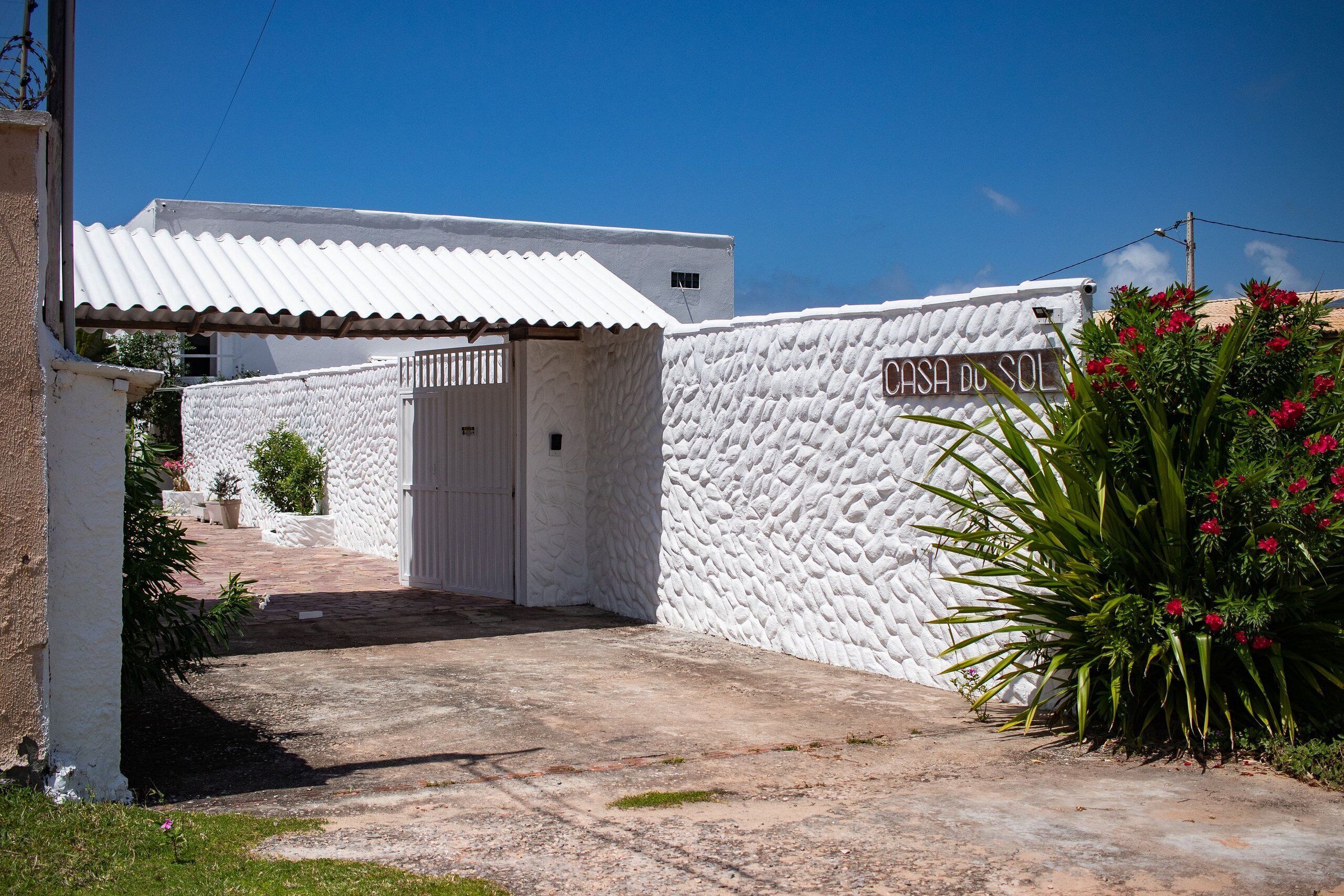 Un edificio blanco con un muro texturizado y un letrero que dice "CASH DO SOL".