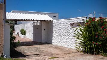 Un edificio blanco con un muro texturizado y un letrero que dice "CASH DO SOL".
