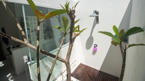 A modern bathroom with a glass shower enclosure, a wooden floor, and a white wall. - Casa do Sol by Carpediem (Ceara-Mirim)
