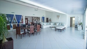 A spacious living area with a dining table and chairs, a sofa, and a coffee table. - Casa do Sol by Carpediem (Ceara-Mirim)