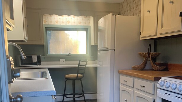 A compact kitchen with a microwave, refrigerator, and stove. - Cozy 1-bedroom apartment in old farm house in historic South Lee (Lee)