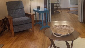 A room with a chair, a lamp, a small table, and a woven basket. - Cozy 1-bedroom apartment in old farm house in historic South Lee (Lee)