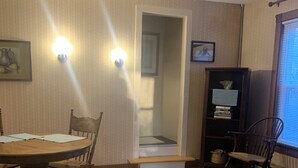 A dining area with a wooden table and chairs, a bench, a bookshelf, and a window with blinds. - Cozy 1-bedroom apartment in old farm house in historic South Lee (Lee)