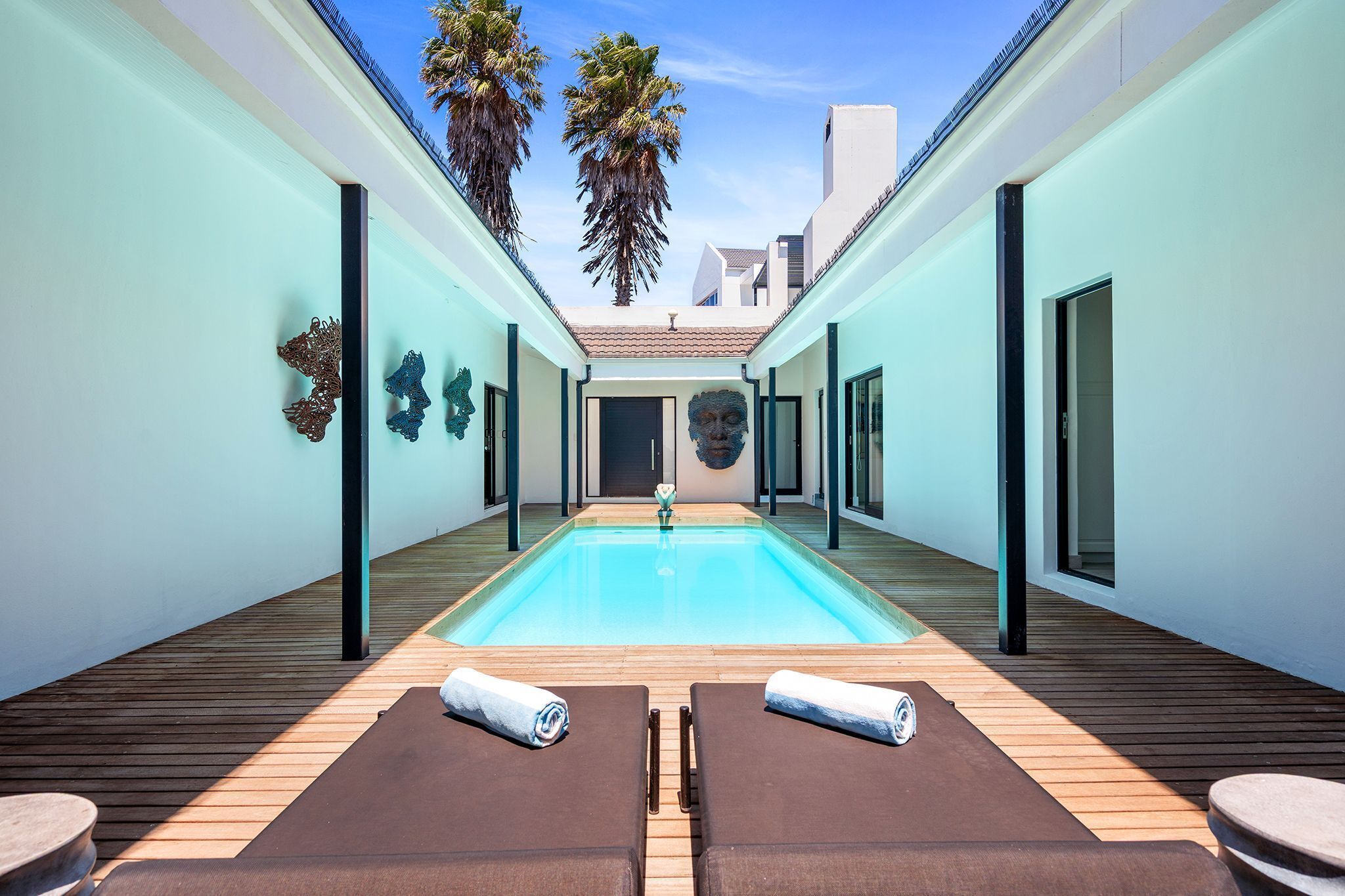 A modern pool area with two lounge chairs and a wooden deck.