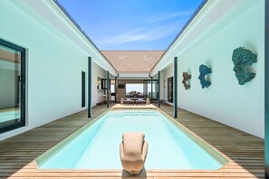 Ein moderner Poolbereich mit freiem Blick auf das Schwimmbecken, einer Holzterrasse und einer Sitzecke mit Tisch und Stühlen.