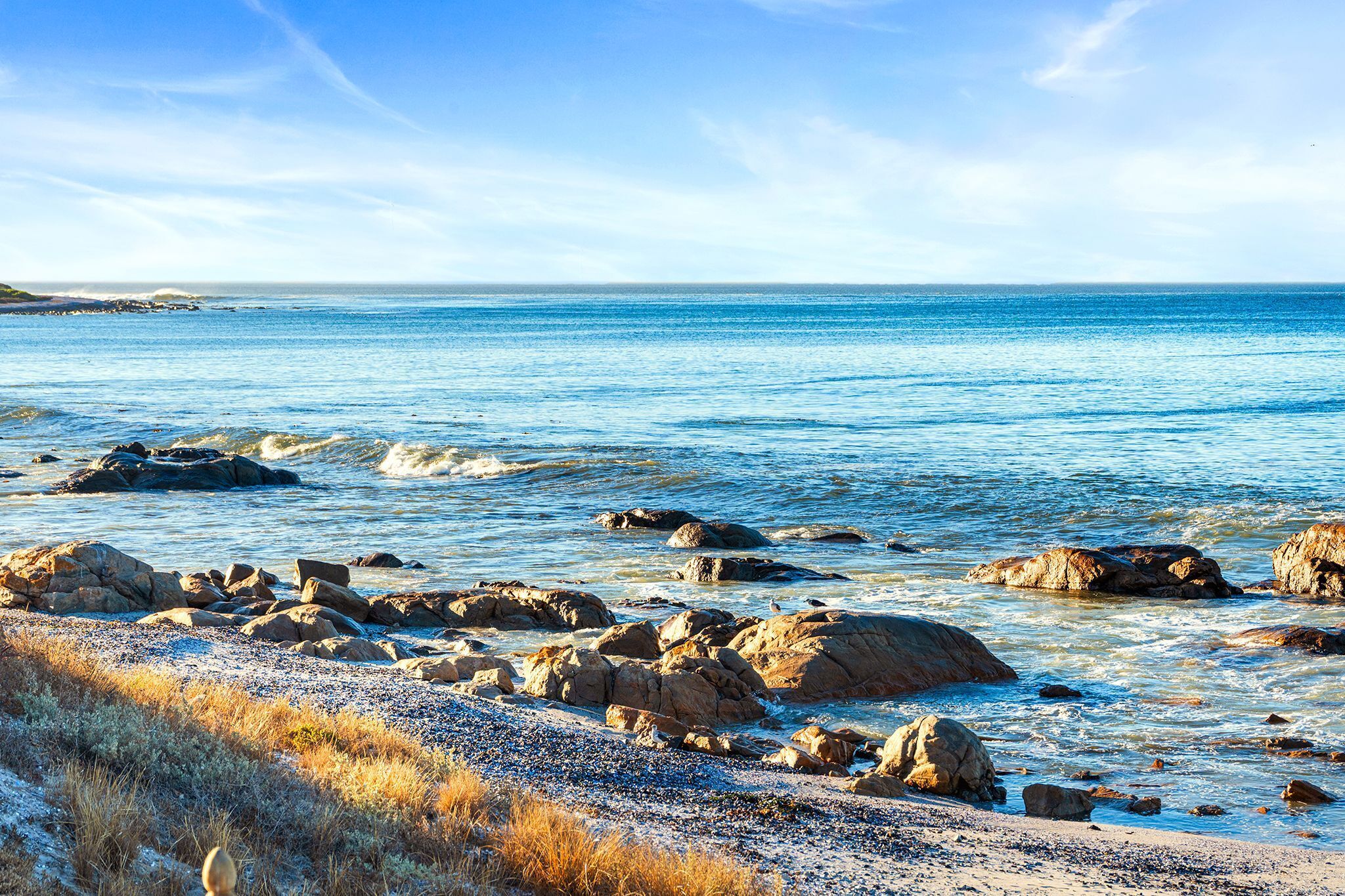 A coastal landscape with rocky shores and clear blue water.