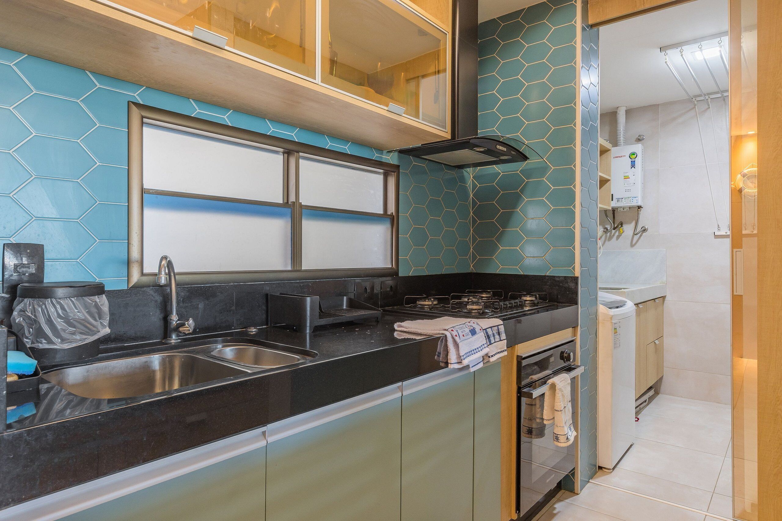 A modern kitchen with a black countertop, stainless steel sink, and a built-in oven.