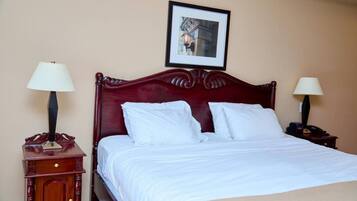 A neatly made bed with white linens, two bedside tables with lamps, and a framed picture on the wall.