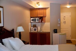 Une chambre d’hôtel équipée d’un lit, d’une lampe de chevet, d’un four à micro-ondes, d’une machine à café et d’un réfrigérateur.