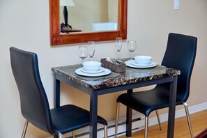 A dining table with four chairs, two wine glasses, and a bowl set on a marble surface.