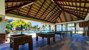 An indoor recreational area with pool tables, a foosball table, and a pool. - Wai Wai #a406 - Beachfront Resort By Carpediem (Caucaia)