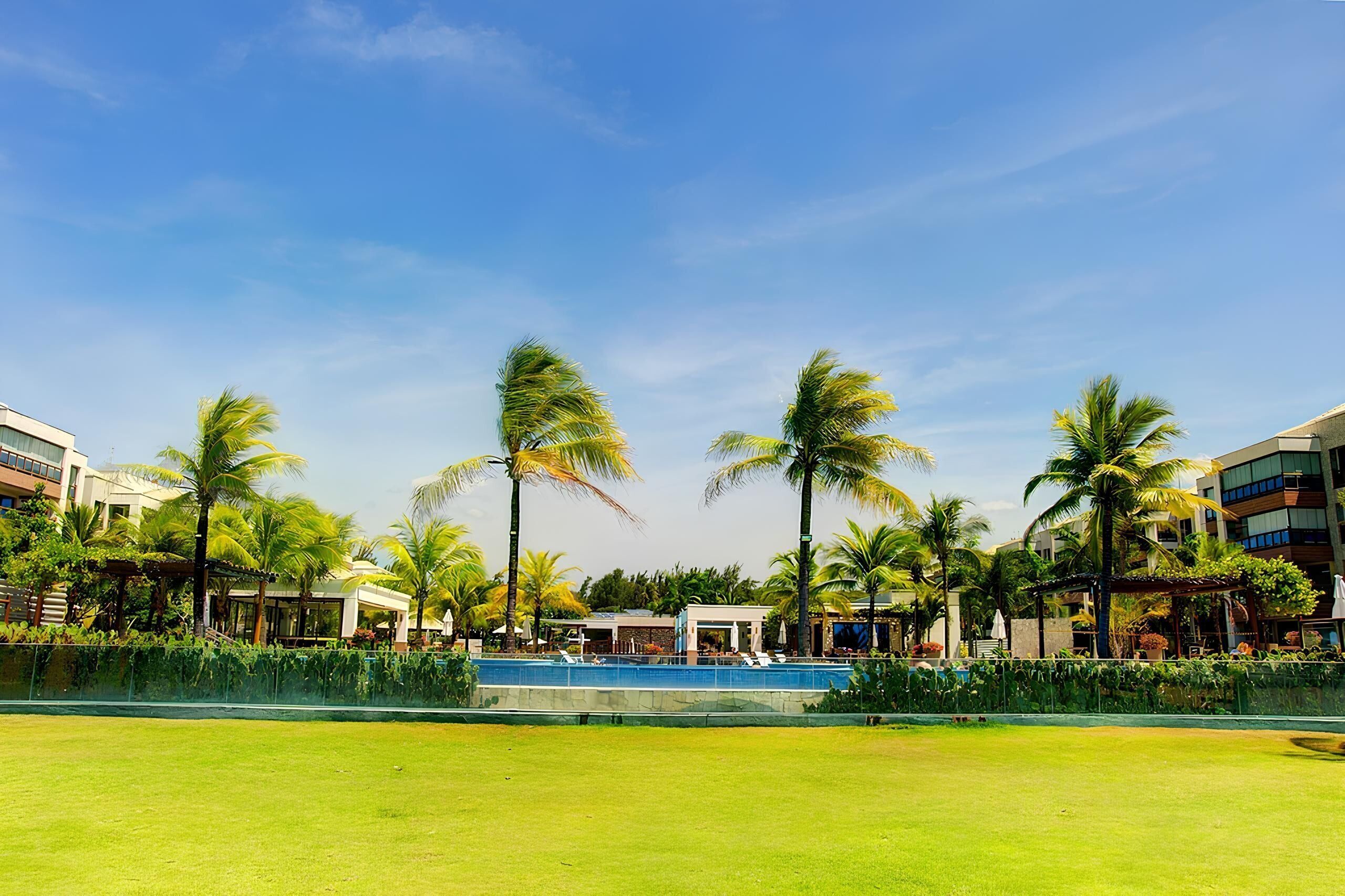 A resort with a swimming pool, palm trees, and modern buildings.