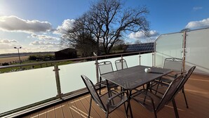 A deck with a table and chairs, overlooking a river and fields. - Vacation apartment 6 persons, near Cloppenburg, bedroom with TV and single beds (Cappeln (Oldenburg))