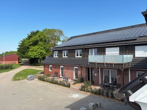 Une maison à deux étages avec un balcon, un garage et une allée menant à une grange rouge.