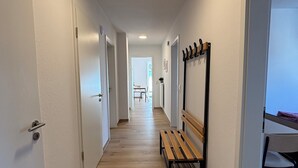 A hallway with wooden flooring, white walls, and a bench. - Vacation apartment 6 persons, near Cloppenburg, bedroom with TV and single beds (Cappeln (Oldenburg))