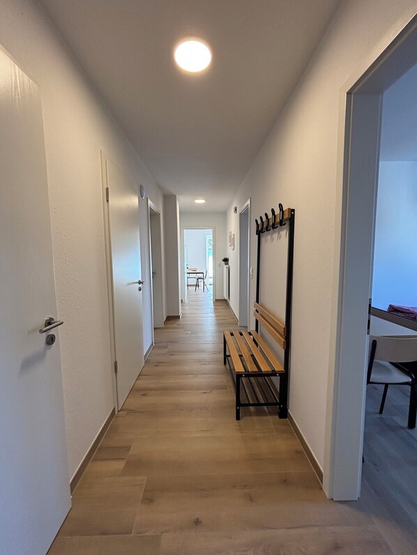 A hallway with wooden flooring, white walls, and a bench. - 3-Bedroom Vacation Rental at the Hammel Vacation Farm in 49692 Sevelten (Cappeln (Oldenburg))