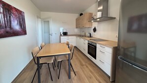A modern kitchen with white cabinets, a wooden countertop, a stainless steel refrigerator, and a dining table with chairs. - Vacation apartment 6 persons, near Cloppenburg, bedroom with TV and single beds (Cappeln (Oldenburg))
