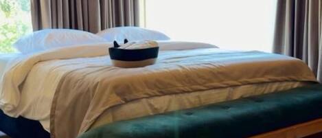 Una habitación con paneles de madera, una cama, un banco y una ventana con cortinas.
