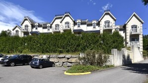 A multi-story building with a consistent architectural style, featuring balconies and a stone retaining wall. - Condo Alpina – 3105 | Cozy Retreat in St-Sauveur (Piedmont)