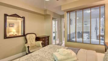 Un dormitorio con cama, una silla, cómoda, espejo y ventana con persianas.