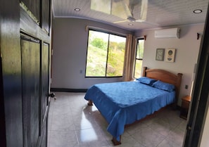 A bedroom with a bed, a window, and a ceiling fan.