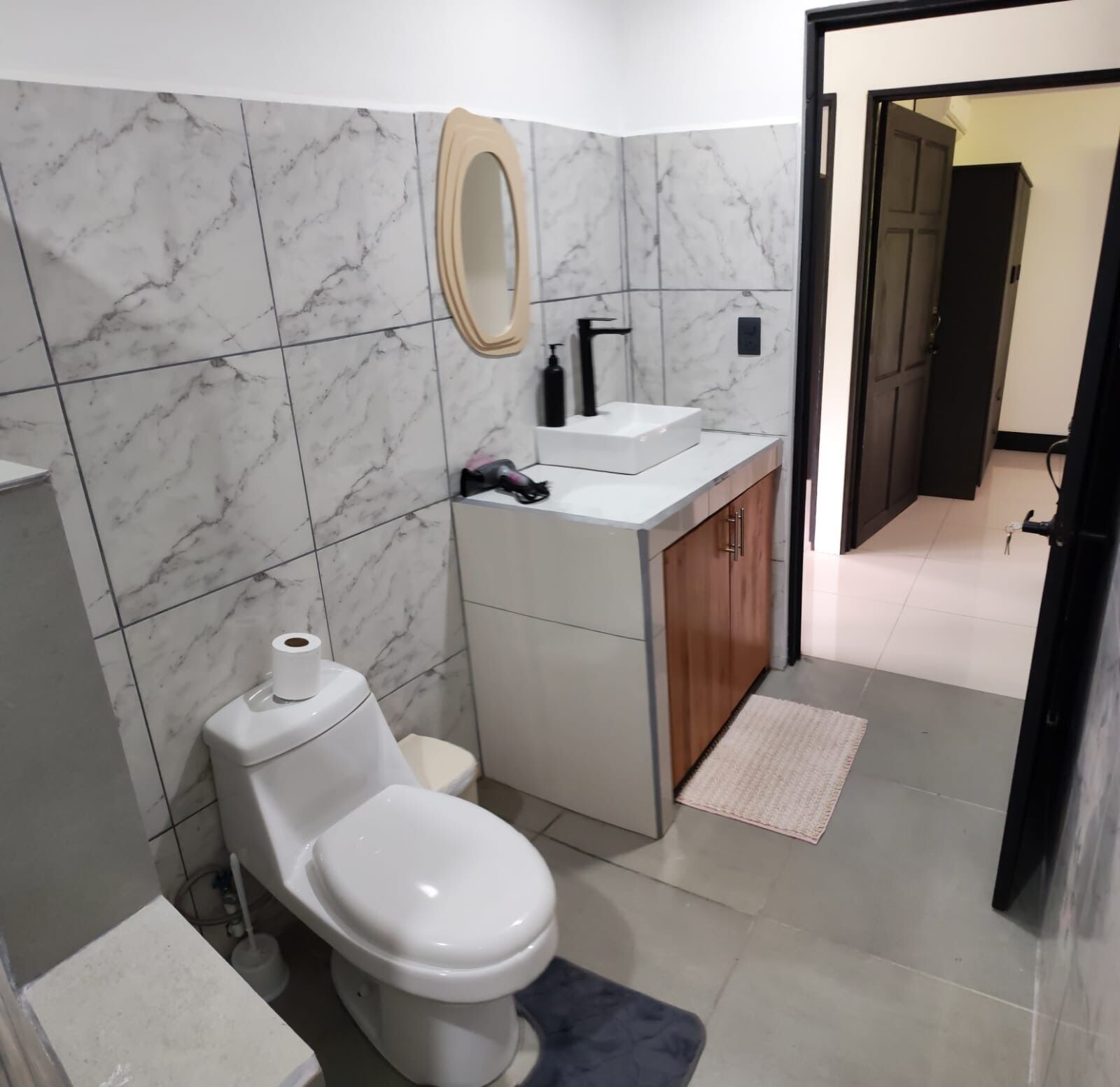 Ein Badezimmer mit Toilette, Waschbecken, Spiegel und Marmorfliesen.