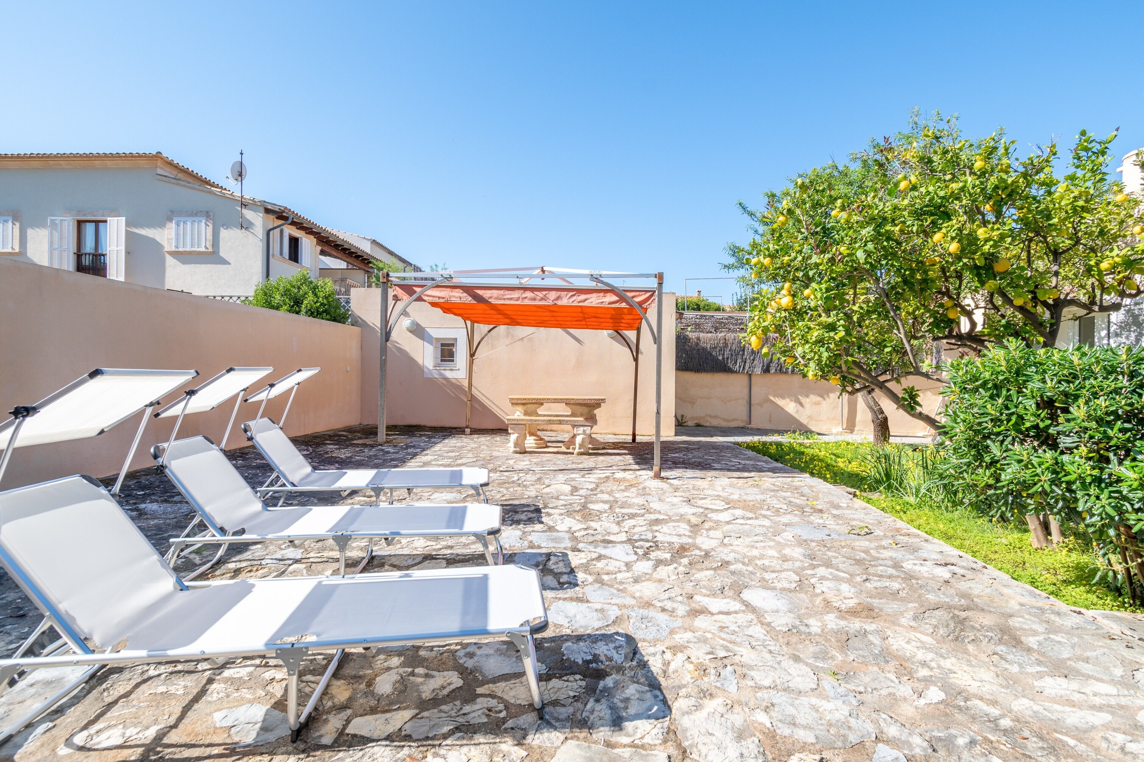 En terrasse med liggestole, et bord og en pergola.