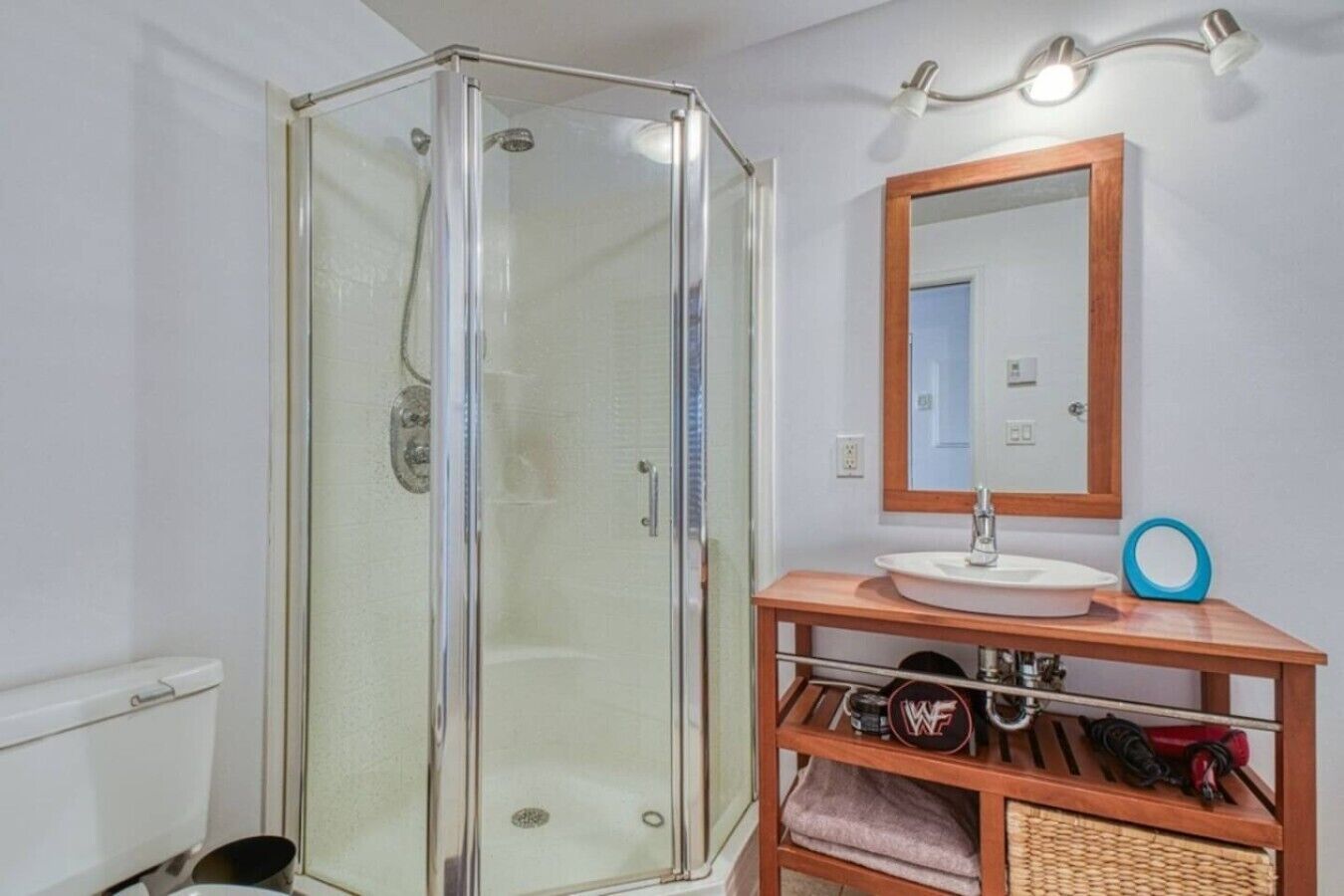 A bathroom with a glass-enclosed shower, a sink with a wooden vanity, and a mirror above the vanity.