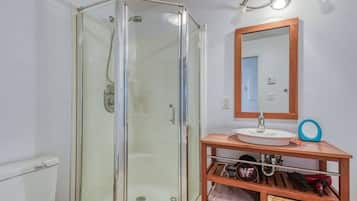 A bathroom with a glass-enclosed shower, a sink with a wooden vanity, and a mirror above the vanity.