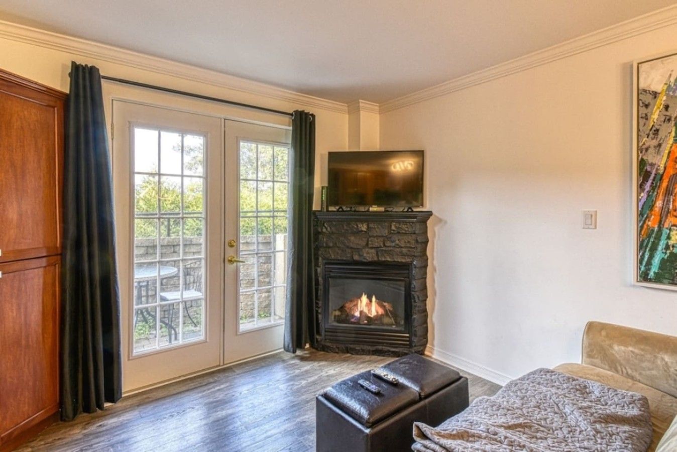 A room with a fireplace, a sofa, a television, and a door leading to an outdoor area.