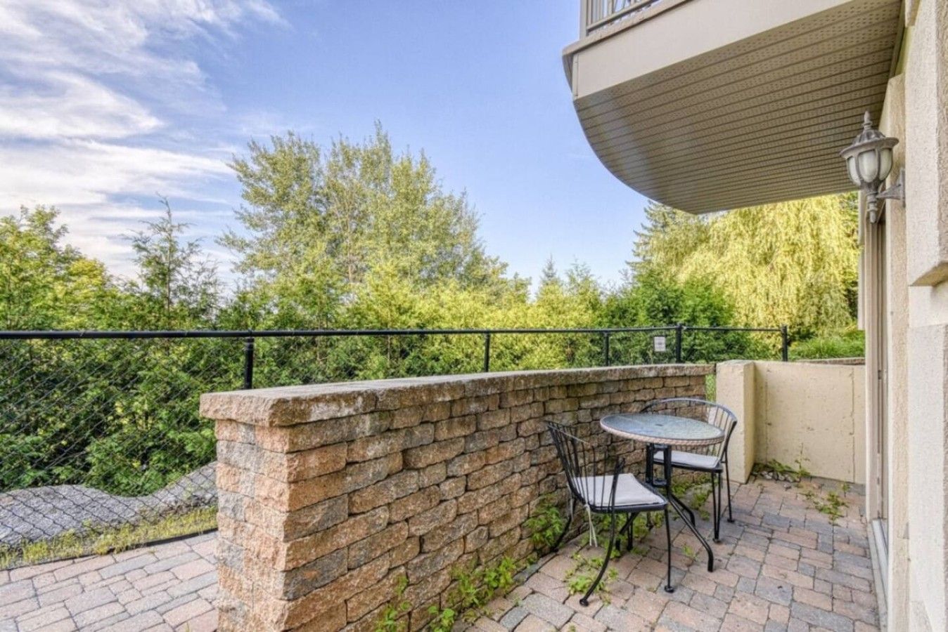 A balcony with a stone wall, a metal table, and a metal chair.