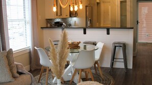A modern kitchen with a dining area, featuring a round table, white chairs, and a decorative plant. - Waterway Getaway - Myrtle Beach (Myrtle Beach)