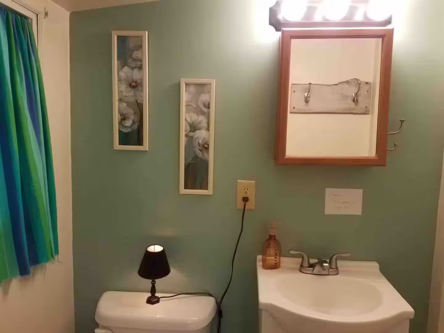 Een badkamer met toilet, wastafel en twee ingelijste bloemenfoto’s aan de muur.