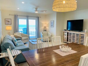 Ein Wohnzimmer mit einem Holzesstisch, zwei Sofas, einem Fernseher und einem Balkon mit Aussicht.