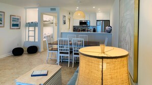 Una cocina moderna con electrodomésticos integrados, un comedor con mesa redonda y sillas, y un rincón de estar acogedor con una lámpara.