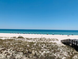 Ein Strand mit weißem Sand, klarem blauen Wasser und einer Holzpromenade.