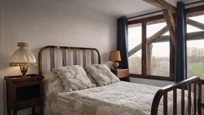 Une chambre à coucher avec un lit en bois, une table de chevet avec une lampe et une fenêtre avec des rideaux.