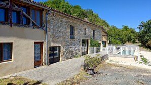 Un bâtiment en pierre doté d’un balcon, d’une entrée fermée par un portail et d’un petit jardin.