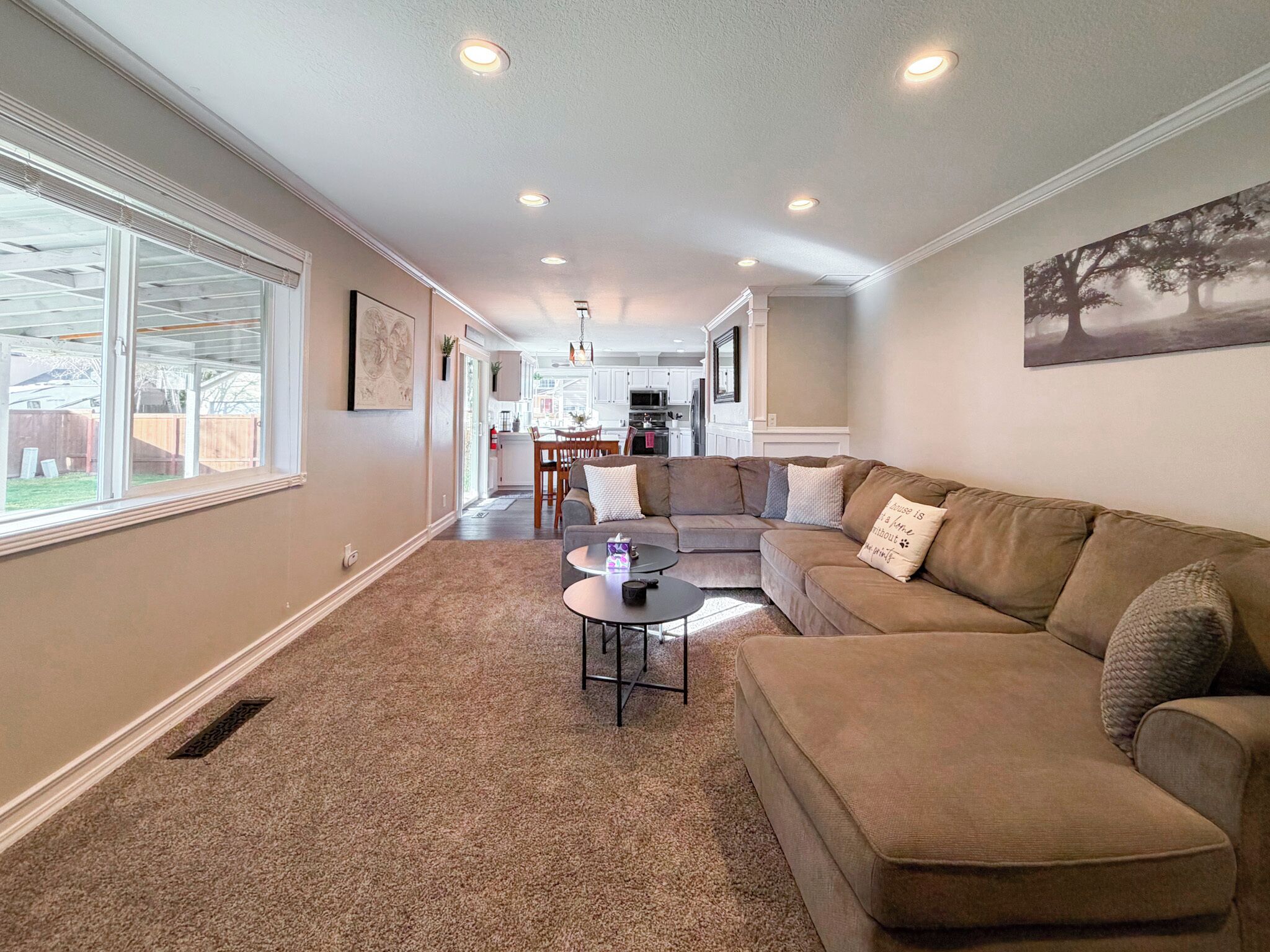 A spacious living room with a large sectional sofa, a coffee table, and a dining area in the background.