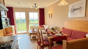 A dining area with a table set for two, a sofa, and a view of the outdoors. - Suite Seensucht am malerischen Brombachsee (Spalt)
