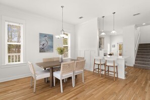 A dining area with a wooden table and chairs, a painting of a bird, and pendant lighting. - Coastal 30A Retreat - 4BR - Sleeps 8 - Walk to Beach (Santa Rosa Beach)