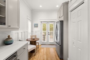 A kitchen with white cabinetry, a wooden dining table, and a refrigerator. - Coastal 30A Retreat - 4BR - Sleeps 8 - Walk to Beach (Santa Rosa Beach)